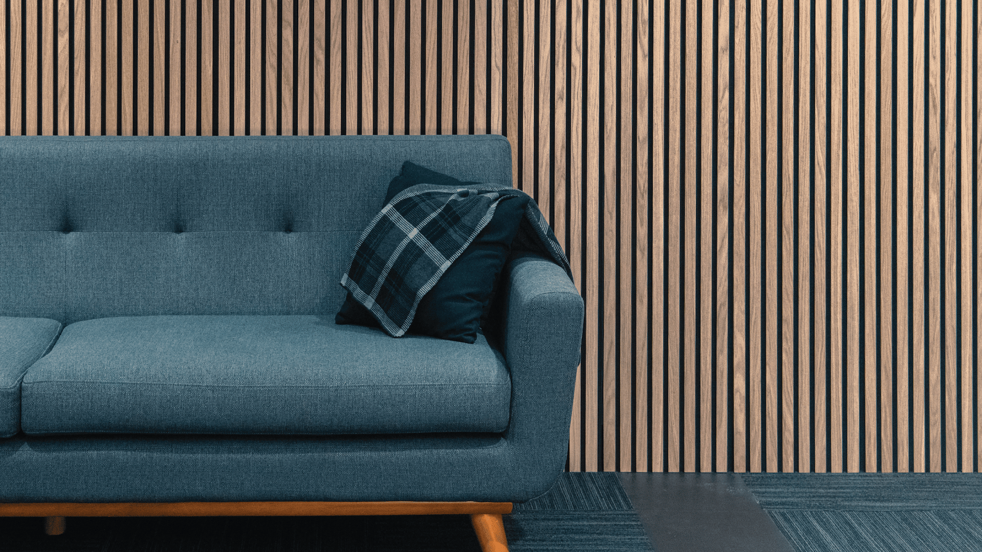 Acoustic wood slat panels behind a grey couch in an office